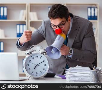 Clown businessman in the office angry frustrated with megaphone and alarm clock. Clown businessman in the office angry frustrated with megaphone