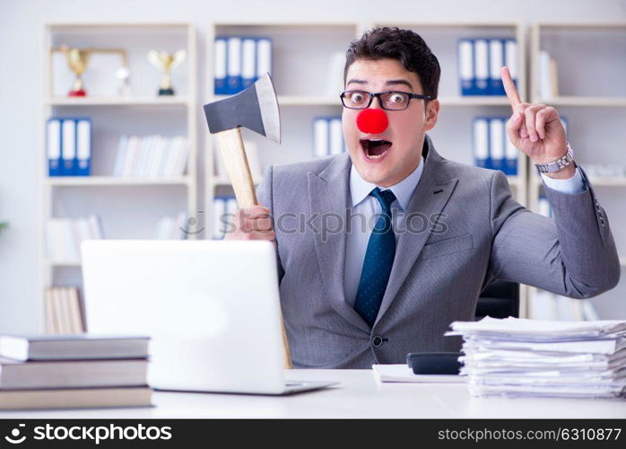 Clown businessman in the office with an axe