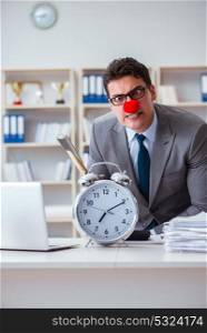 Clown businessman in the office with an axe and an alarm clock