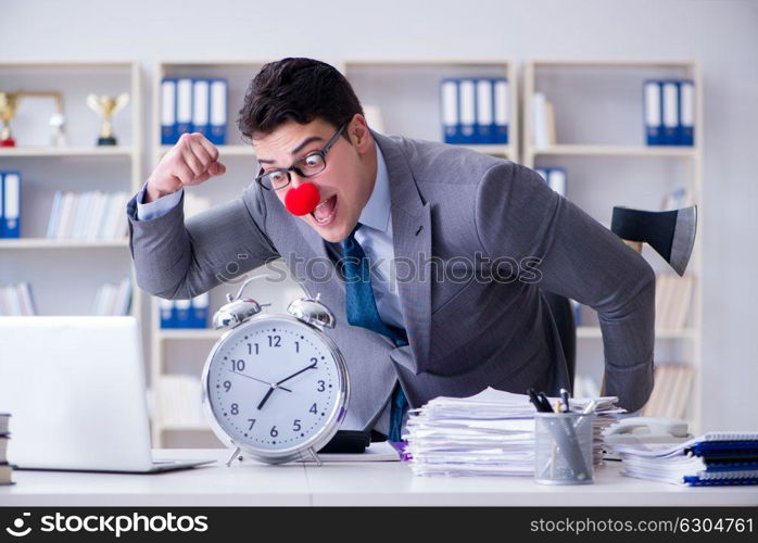 Clown businessman in the office with an axe and an alarm clock