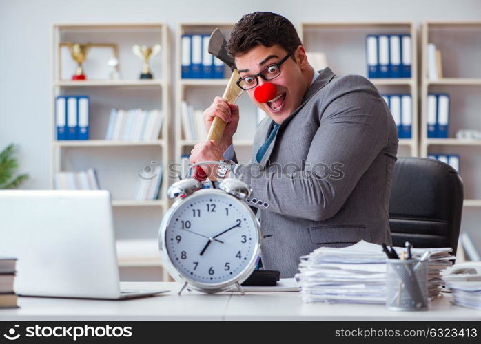 Clown businessman in the office with an axe and an alarm clock