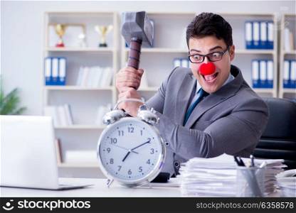 Clown businessman in the office with hammer and an alarm clock