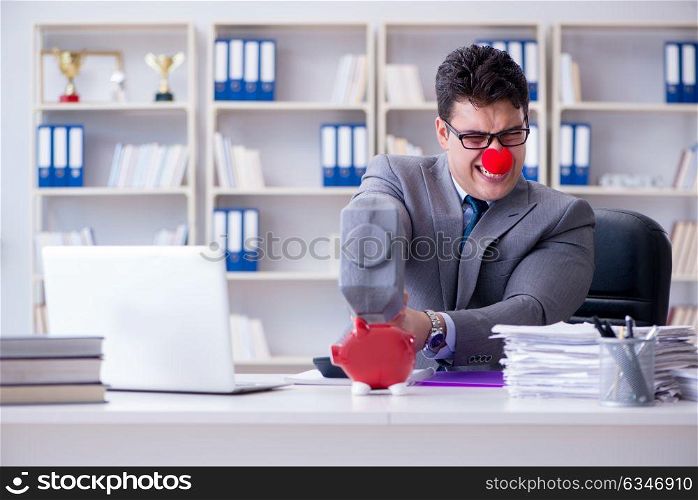Clown businessman with a piggy bank and a hammer