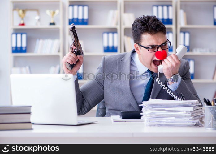 Clown businessman working in the office angry frustrated with a . Clown businessman working in the office angry frustrated with a gun