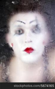 clown face in theatrical makeup through frosty glass