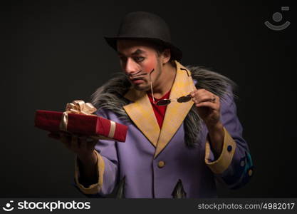 Clown man with Christmas gift box on black background