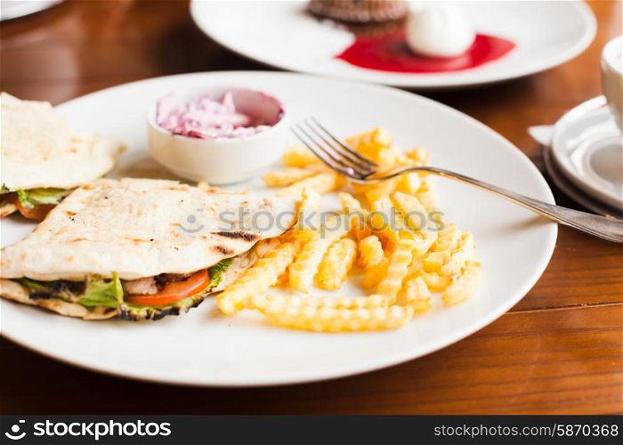 Club sandwich in pita with fried potato and salad