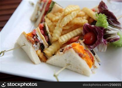 Club sandwich with chicken breast , bacon , tomato , cucumber and fried potatoes