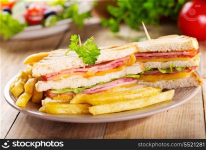 club sandwiches with french fries on wooden table