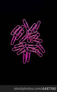 Cluster of bright pink paperclips on a black background