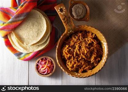 Coχnita Pibil. Tyπcal Mexican stew from Merida, Yucatan, made from pork marinated with aχote and≥≠rally accompanied with beans and red onion with haba≠roχli, it can be eaten in tacos.