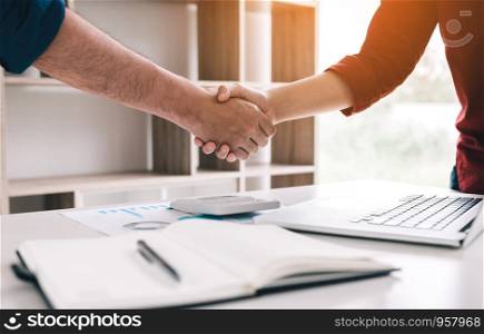 Co-worker startup shaking hands with colleagues in home office.