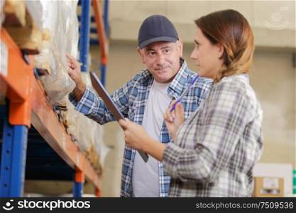 co-workers in a warehouse checking inventory levels of goods