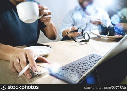 co working creative designers working at office and holding a cup of coffee,working on smart phone and digital tablet computer docking on smart keyboard,filter film effect