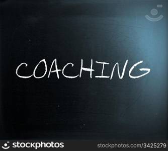 ""Coaching" handwritten with white chalk on a blackboard."