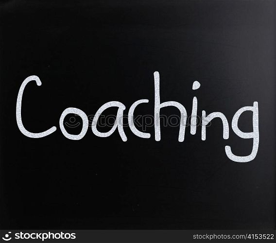 ""Coaching" handwritten with white chalk on a blackboard"