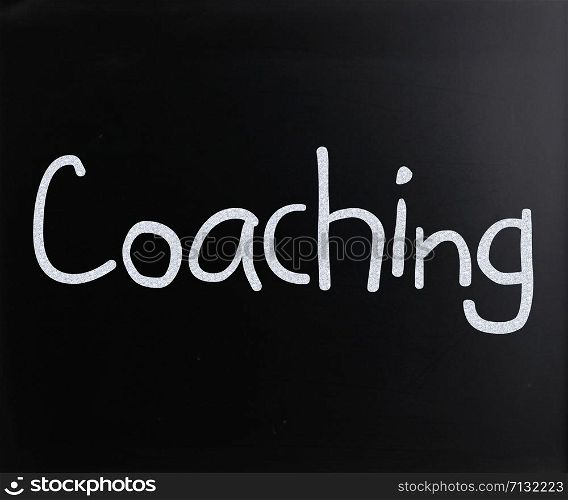 ""Coaching" handwritten with white chalk on a blackboard"