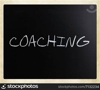 ""Coaching" handwritten with white chalk on a blackboard."