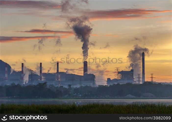 Coal power plant and steam from the flue in the beautiful morning among the mountains and lakes. Mae Moh, Lampang, Thailand. Lines a row high voltage pole.. Coal power plant and lake.
