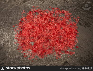 Coarse brightly pink food salt from Sri Lanka on a stone background. Coarse brightly pink food salt from Sri Lanka on a stone background.