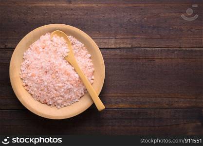 Coarse pink Himalayan salt on wooden plate with wooden spoon, photographed overhead with copy space on the side . Coarse Pink Himalayan Salt