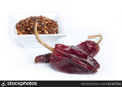 Coarsely ground red pepper and whole dried peppers.White isolated