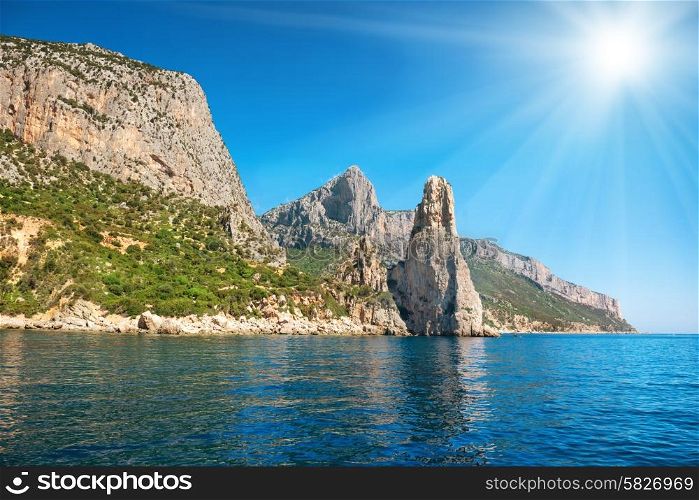 Coast and blue Mediterranean sea and bright sun on the sky in Sardinia, Italy. View from the yacht
