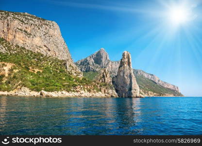 Coast and blue Mediterranean sea and bright sun on the sky in Sardinia, Italy. View from the yacht