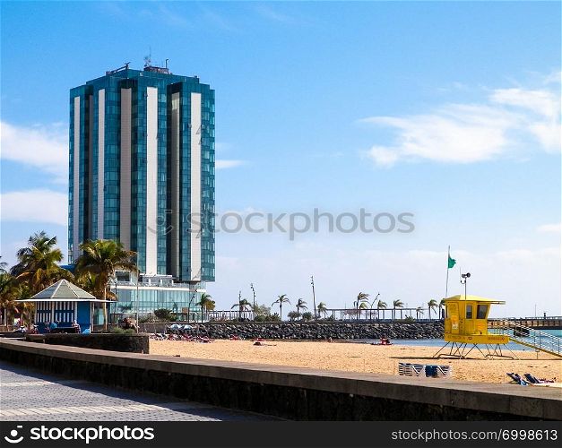 Coast of Arrecife, capital city of Lanzarote island, Canarian Is. Beach, palms as tropical nature and modern buildings in a background.. Coast of Arrecife, Lanzarote, Canarian Islands.