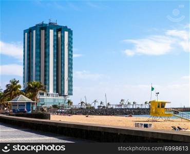 Coast of Arrecife, capital city of Lanzarote island, Canarian Is. Beach, palms as tropical nature and modern buildings in a background.. Coast of Arrecife, Lanzarote, Canarian Islands.