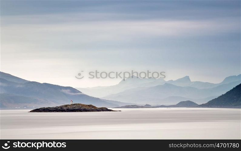 Coast of Norway sea in clouds of haze. Beacon on a rock. Cloudy Nordic day on Lofoten islands