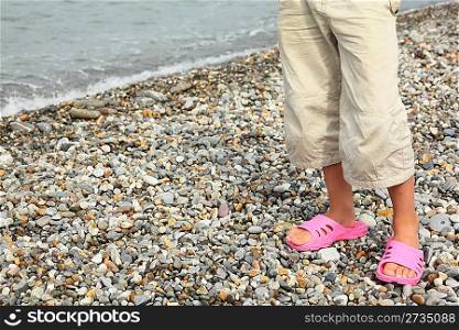 coast of sea. legs of child with slippers. focus on right footstep.