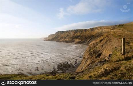 Coastal landscape at sunrise with cliffs and misty glow