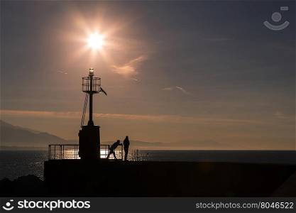 Coastal landscape with lighthouse in backlight in the morning with people in relaxation