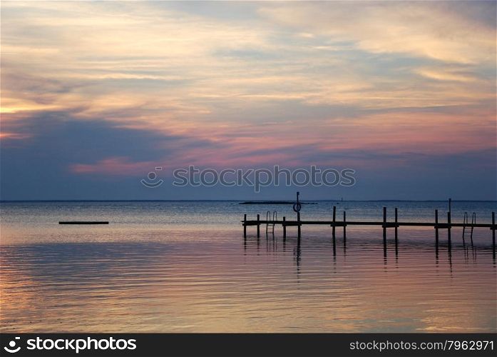 Coastal view with a bathing pier silhouette at sunset