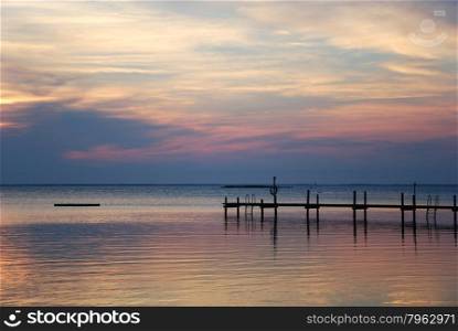 Coastal view with a bathing pier silhouette at sunset