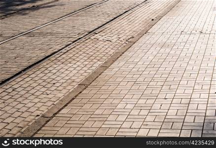 Cobblestone road in the sunlight with tram&rsquo;s rails