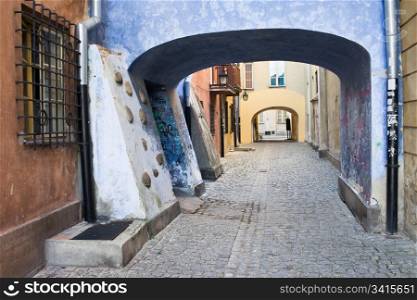 Cobblestone street with arched passage in the Old Town (Polish: Stare Miasto, Starowka) of Warsaw, Poland
