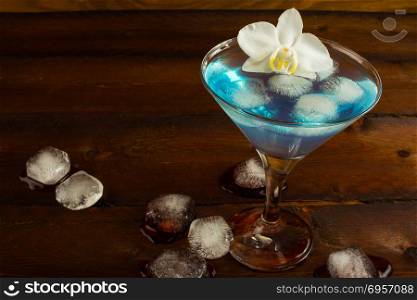 Cocktail Blue Martini on the dark wooden background. Blue cocktail. Blue Martini. Blue Hawaiian cocktail. Blue curacao liqueur. Blue margarita. Cocktail Blue Martini on the dark wooden background