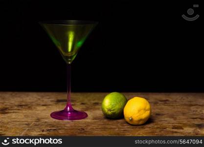 Cocktail glass and lemon and lime against black background