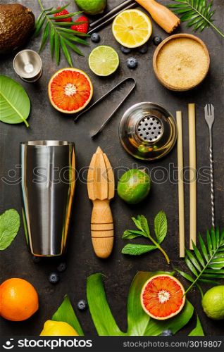 Cocktail making bar tools, shaker, tropical fruits and leaves on a dark background. Top view. Cocktail making bar tools, shaker, tropical fruits and leaves