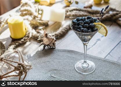 Cocktail with bluberriy in martini glass on bright wooden table. Cocktail with bluberriy in martini glass on wooden table