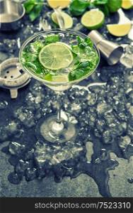 Cocktail with lime, mint and ice. Bar drink accessories. Vintage style toned picture
