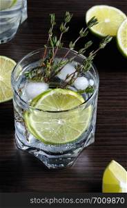Cocktail with white rum and tonic, a slice of lime and thyme