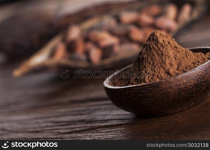 Cocoa beans in the dry cocoa pod fruit on wooden background. Cacao beans and powder and food dessert background