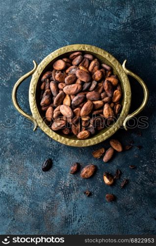 Cocoa beans on dark background, top view, copy space, flat lay