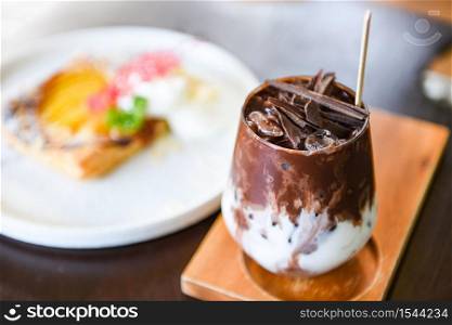 cocoa drink and chocolate / tasty milk shake with ice cocoa in glass on wood background