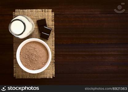 Cocoa or chocolate drink powder in bowl with bottle of milk on the side, photographed overhead with natural light (Selective Focus, Focus on the chocolate powder). Cocoa or Chocolate Drink Powder
