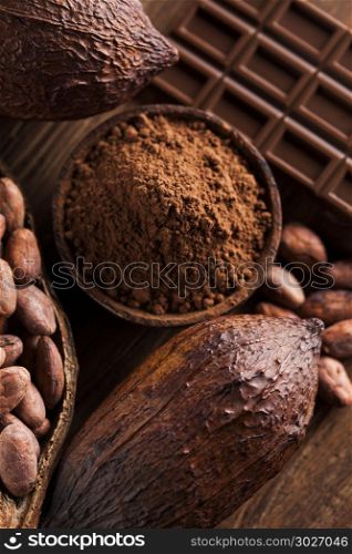 Cocoa pod and chocolate bar and food dessert background. Chocolate bar, candy sweet, cacao beans and powder on wooden background