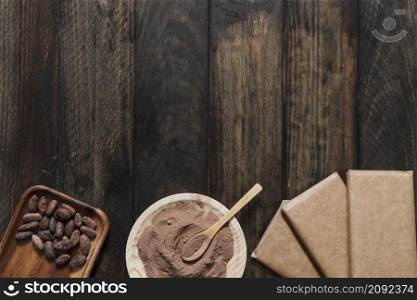 cocoa powder beans with wrapped chocolate bar wooden table